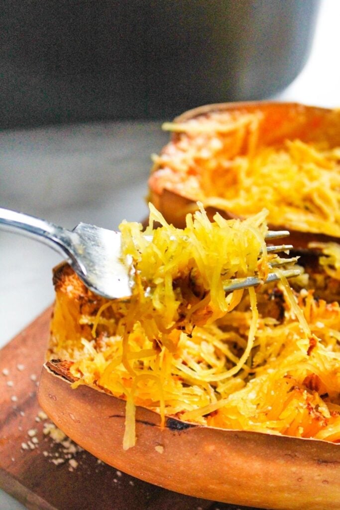 Spaghetti Squash cortado ao meio com um garfo tirando um pedaço de abóbora