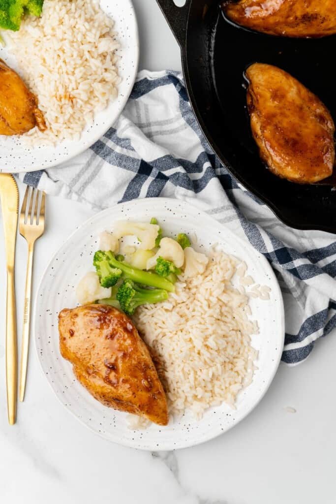 Visão aérea de arroz de peito de frango, brócolis e couve-flor em um prato branco.