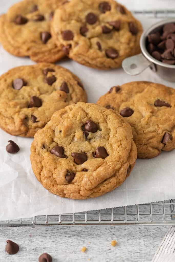 Biscoitos de pepitas de chocolate assados ​​em uma grade de resfriamento forrada com papel manteiga.