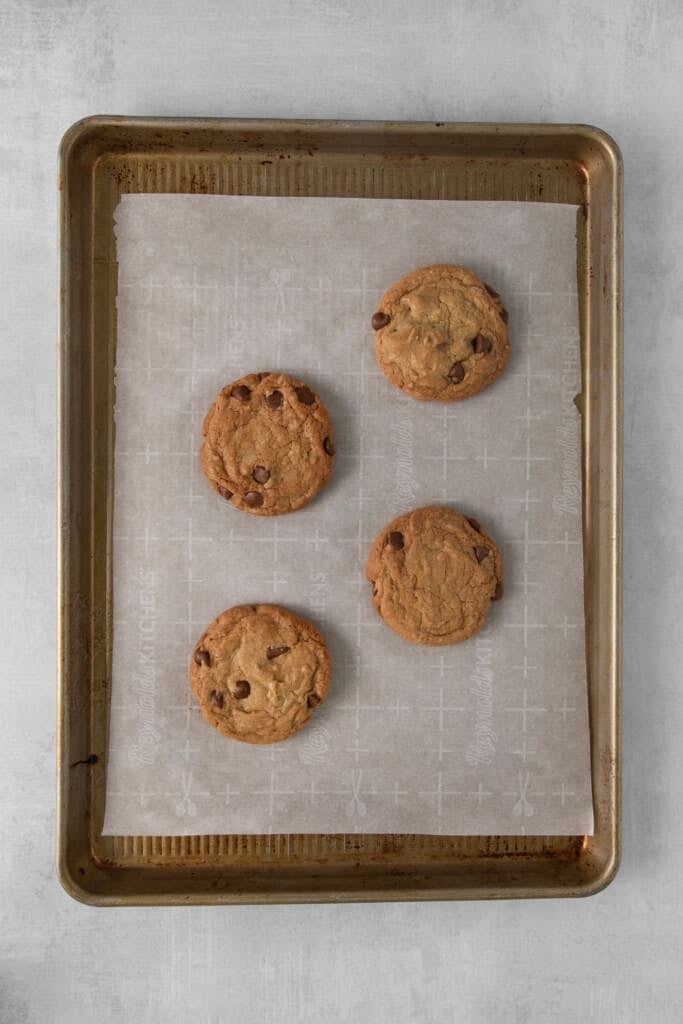 Assadeira forrada com papel manteiga com 4 biscoitos de chocolate assados.