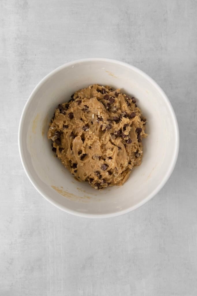 Visão aérea de bicarbonato de sódio, sal, farinha e pedaços de chocolate depois de misturados.