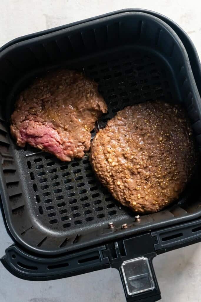 Visão aérea de dois bifes de cubo em uma cesta de fritadeira.