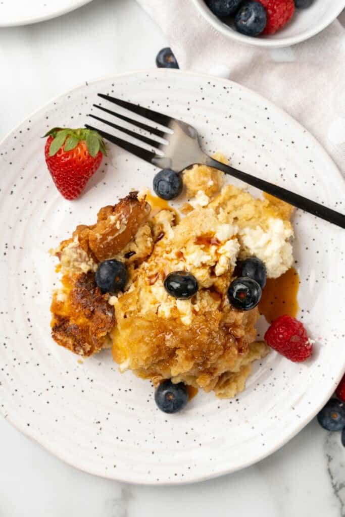 Visão aérea da caçarola de rabanada Crockpot em um prato branco com frutas e um garfo.