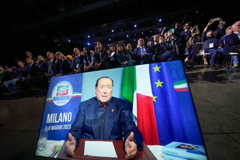 Ativistas do partido Forza Italia assistem Silvio Berlusconi enquanto ele fala em seu vídeo durante uma convenção do partido Forza Italia em Milão