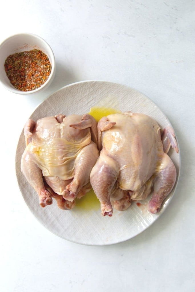 Azeite regado em cima da galinha da Cornualha e temperos misturados em uma tigela pequena
