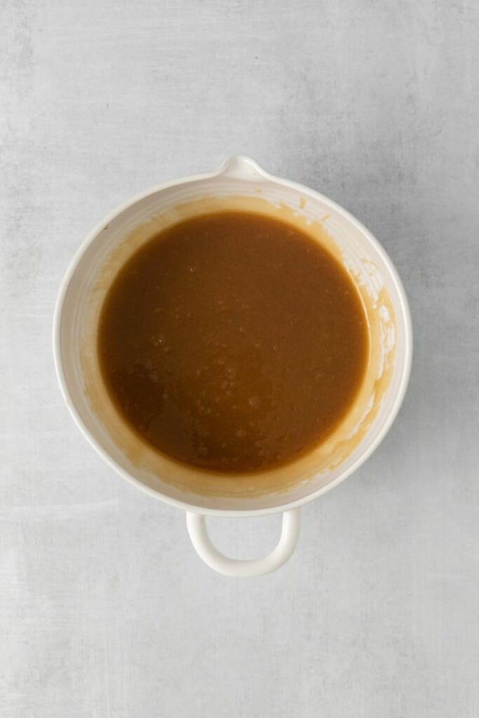 Xarope de bordo, açúcar mascavo e manteiga derretida em uma tigela branca.