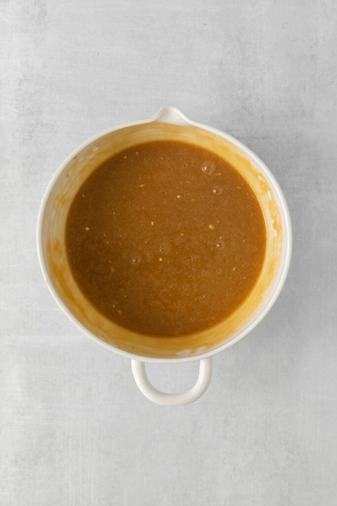 Adicionar ovos, farinha e baunilha à mistura de xarope de bordo em uma tigela branca.