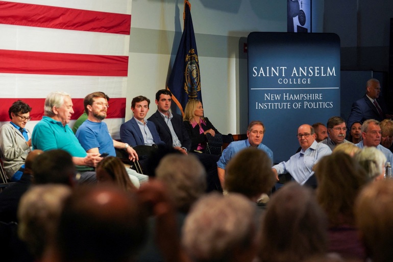As pessoas sentam-se em frente a uma bandeira gigante dos Estados Unidos no Saint Anselm College.