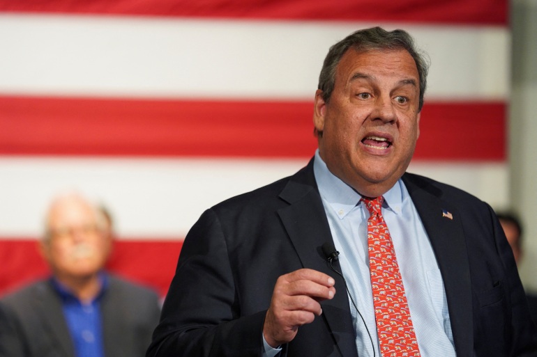 Chris Christie fala contra uma bandeira gigante dos EUA.