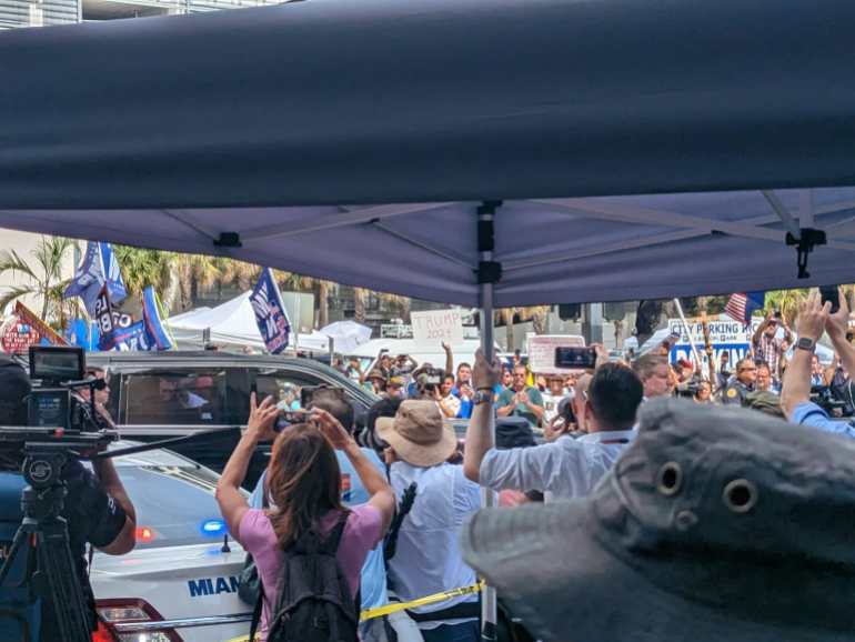 Pessoas tiram fotos do carro que transportava o ex-presidente Donald Trump quando ele sai do tribunal