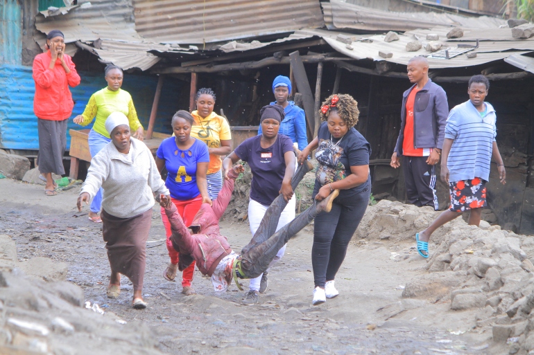 Um grupo de mulheres carrega um homem ferido durante protestos para um hospital próximo em Mathare, Nairóbi, Quênia