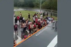 Torcedores do Flamengo observam ônibus tombado na beira da Rodovia Dutra