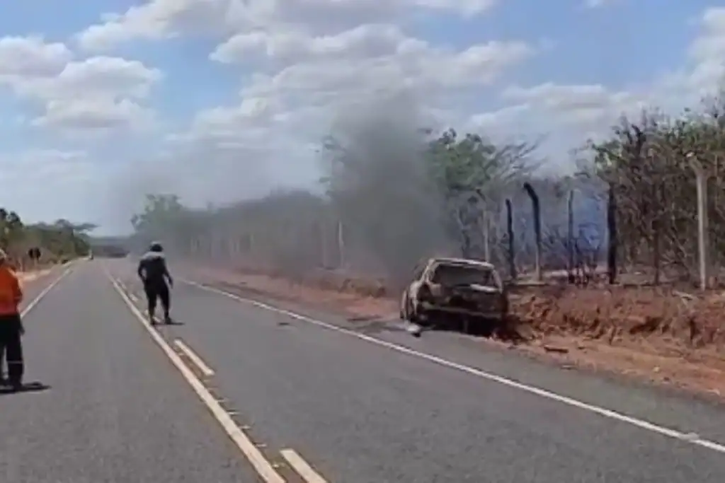 Foto do veículo completamente destruído e carbonizado após colisão na rodovia.