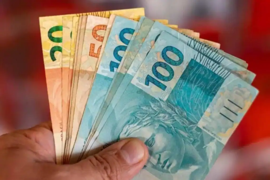 Cédulas de dinheiro na mão de um aposentado, representando o ressarcimento do BMG