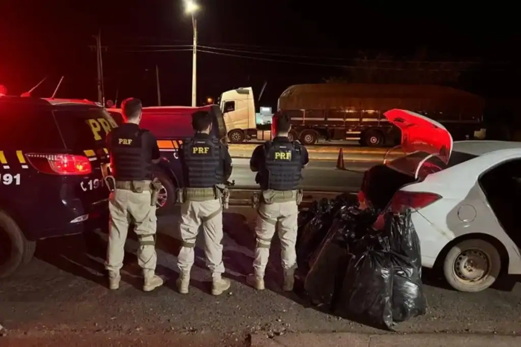 Policiais da PRF ao lado de sacos de maconha apreendida em Picos, Piauí.