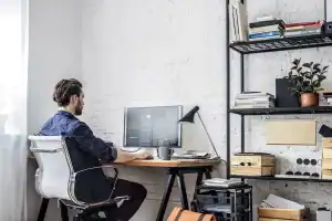 Profissional usando notebook em mesa com cadeira ergonômica no home office