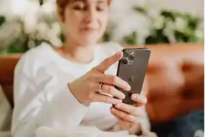 Mulher com telefone na mão se informando sobre compra de dólar.