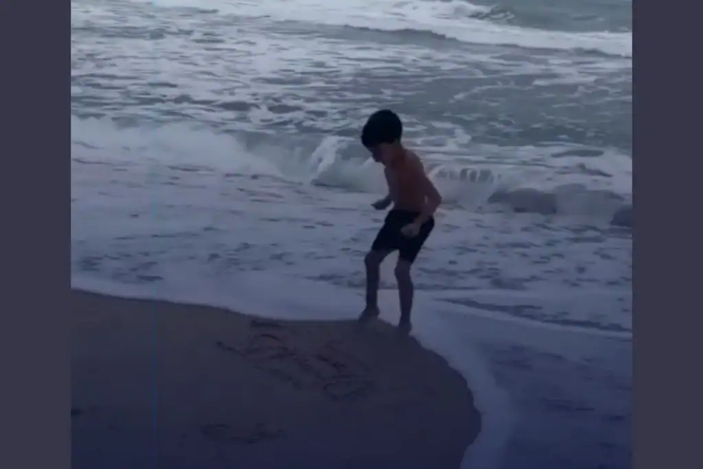 Menino na praia se divertindo na areia