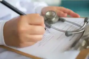 Uma mão adulterando um carimbo de atestado médico com o símbolo da lei ao fundo