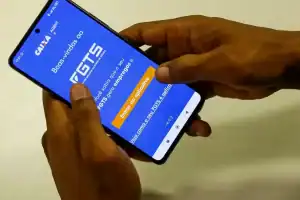 Trabalhador analisando tela de celular com opções de linha de crédito e crédito