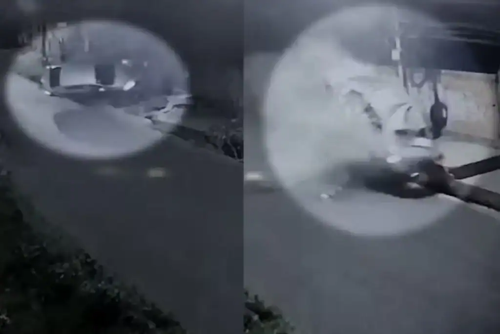 Foto em preto e branco de carro capotado após atingir poste na rua