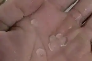 Morador de Arraial segura pedras de granizo na palma da mão, após o temporal no interior do Piauí.