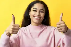Foto de uma mulher sorrindo e acenando positivamente com a mão, em um gesto de confiança na compra segura do diploma