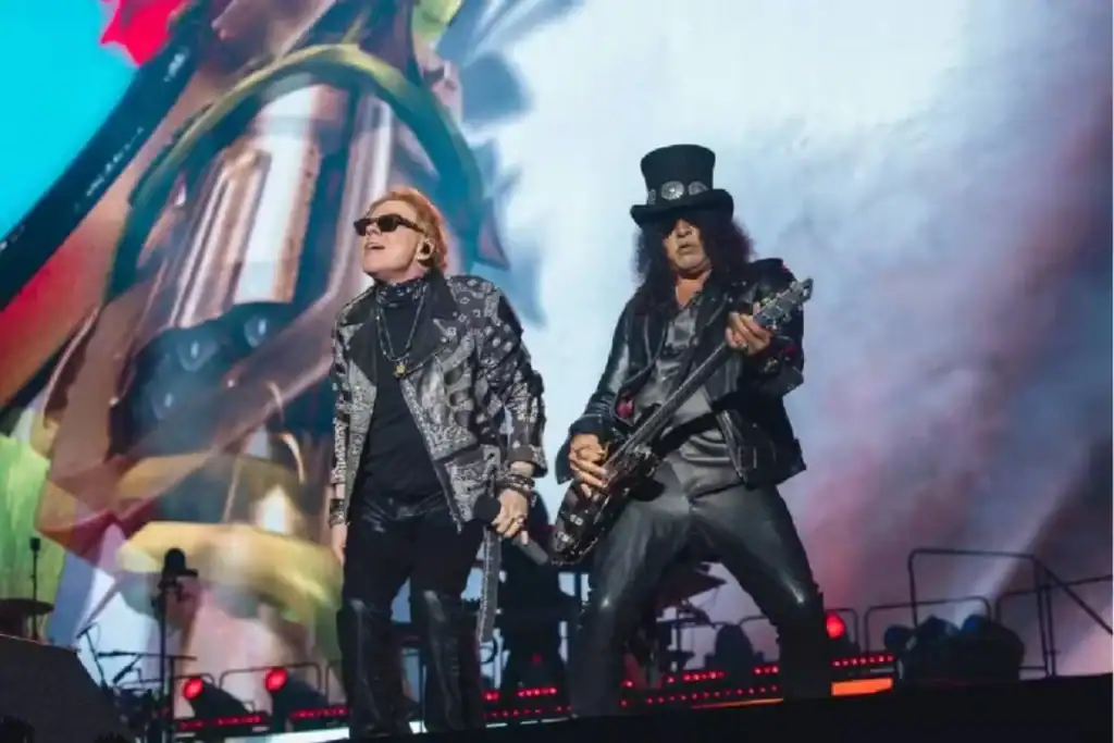 Axl Rose, Slash e Duff McKagan, membros do Guns N' Roses, tocando no palco durante show da turnê mundial.