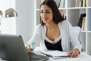 Mulher jovem estudando gestão em um curso online via notebook.