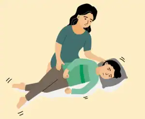 Pessoa prestando primeiros socorros a outra deitada no chão durante uma crise epiléptica, com foco na segurança e apoio.