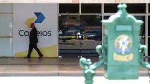 Logo dos Correios com representação de dinheiro e gráficos financeiros, simbolizando o empréstimo de R$ 12 bilhões para recuperação fiscal da estatal.