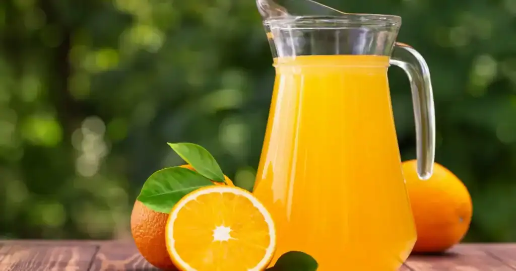 Copo de suco de laranja natural com laranjas frescas, foco de estudo da USP sobre saúde do coração.