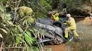 Carro acidentado na BR-050 em Goiás, caído em ribanceira, com equipes de resgate e bombeiros atuando no local.