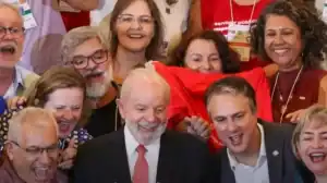 Professores da educação pública brasileira protestam contra proposta de reajuste salarial de 0,37% para 2026, segurando cartazes e faixas em manifestação.