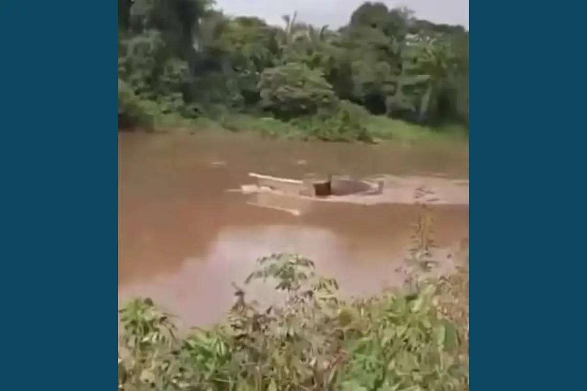 Caçamba branca parcialmente submersa no Rio Itapecuru, ao lado de uma balsa de madeira, após acidente em Pirapemas, <a href=