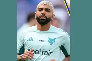 Atacante Gabigol vestindo a camisa do Santos, sorrindo, em campo, após o anúncio de seu retorno por empréstimo.
