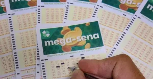 Bilhete da Mega-Sena com os números 01, 02, 05, 14, 18, 32 e pilhas de notas de dinheiro
