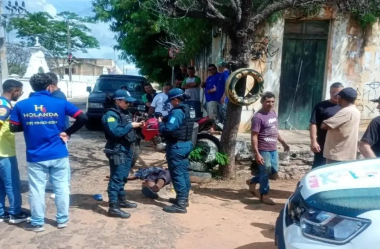 Motocicleta Yamaha caída na calçada ao lado de uma árvore após acidente na BR-230, em Oeiras (PI), com equipes de resgate e da polícia no local.