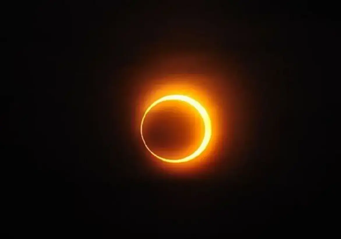 Imagem de um eclipse solar total, mostrando a silhueta escura da Lua cobrindo completamente o Sol e revelando a coroa solar brilhante ao redor, em um céu escurecido.
