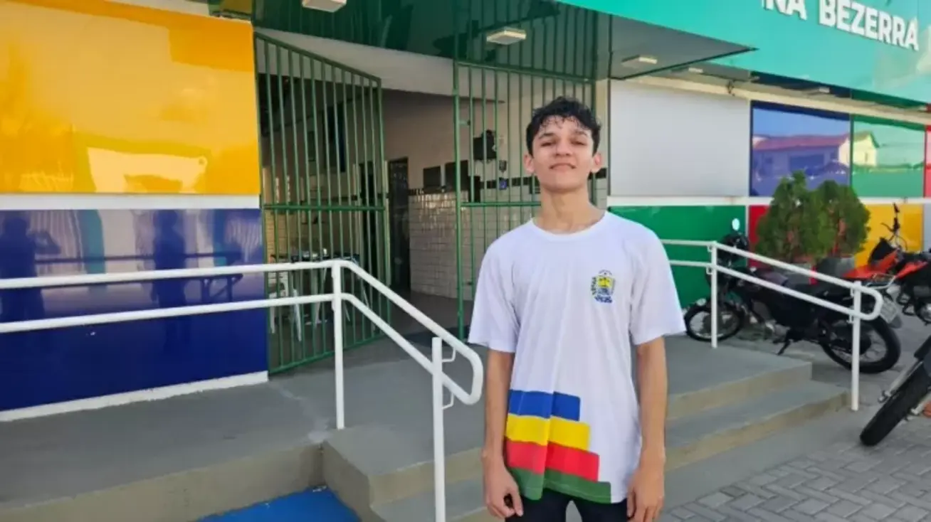Aluno de escola pública em Teresina é contratado por multinacional para dar aulas de programação 1 Jovem estudante Jhonata Lima Silva sentado em frente a um computador com linhas de código na tela, em um ambiente de estudo.